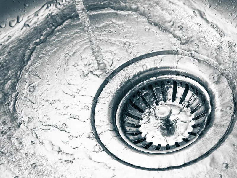 Water draining cleanly through a stainless steel kitchen sink strainer