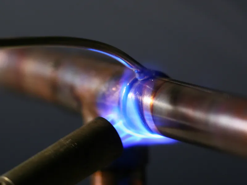 A technician soldering a copper pipe joint during a main line repair